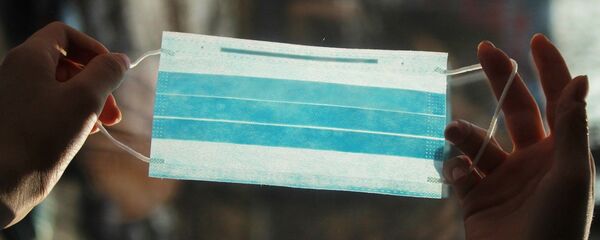 Una mascarilla en las manos, referencial - Sputnik Mundo