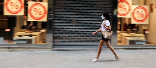 Una mujer con una máscara facial pasa junto a una tienda cerrada en la ciudad de Lleida. 13 de julio de 2020 - Sputnik Mundo