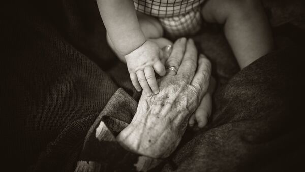 Las manos de un bebé y de una persona mayor - Sputnik Mundo