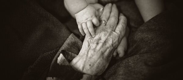 Las manos de un bebé y de una persona mayor - Sputnik Mundo