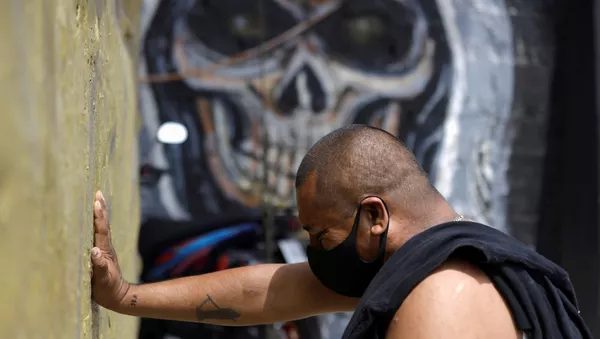 Un hombre con mascarilla rezando a la Santa Muerte en Ciudad de México - Sputnik Mundo