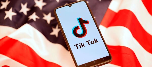Un 'smartphone' con el logo de TikTok en la pantalla encima de una bandera estadounidense - Sputnik Mundo
