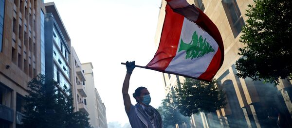 Un hombre con la bandera del Líbano durante las protestas en Beirut - Sputnik Mundo