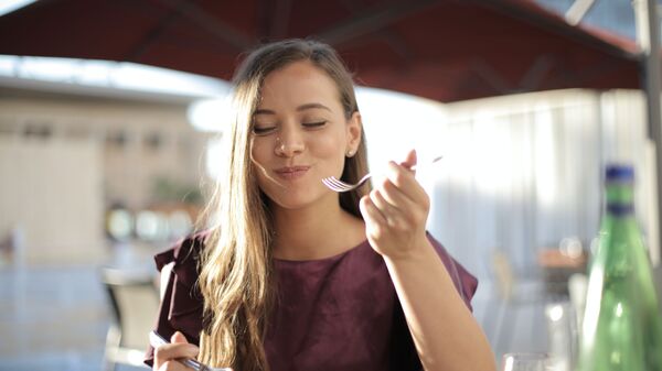 Una mujer comiendo - Sputnik Mundo