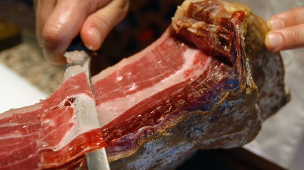 Un hombre corta un jamón ibérico - Sputnik Mundo