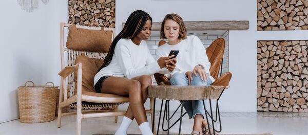 Jóvenes con un 'smartphone', imagen referencial - Sputnik Mundo