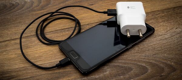 Un teléfono con su cargador - Sputnik Mundo