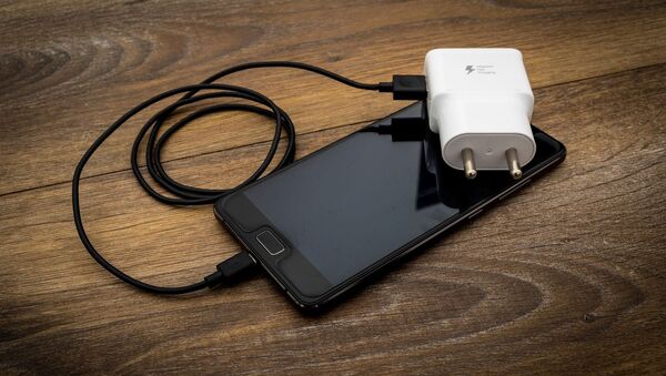 Un teléfono con su cargador - Sputnik Mundo