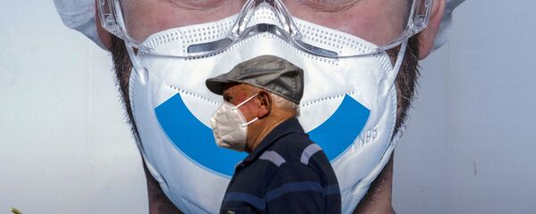 Un hombre con mascarilla pasa junto a un anuncio de una clínica privada en Barcelona - Sputnik Mundo