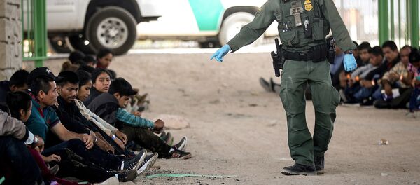 Un agente de Aduanas y Protección Fronteriza de Estados Unidos junto a migrantes detenidos en El Paso, EEUU - Sputnik Mundo