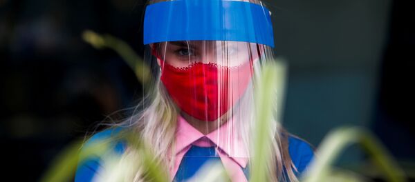 Una mujer con una máscara protectora y una mascarilla para protegerese del COVID-19 en Moscú (archivo) - Sputnik Mundo