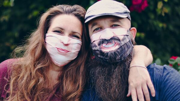 Una pareja con divertidas mascarillas - Sputnik Mundo