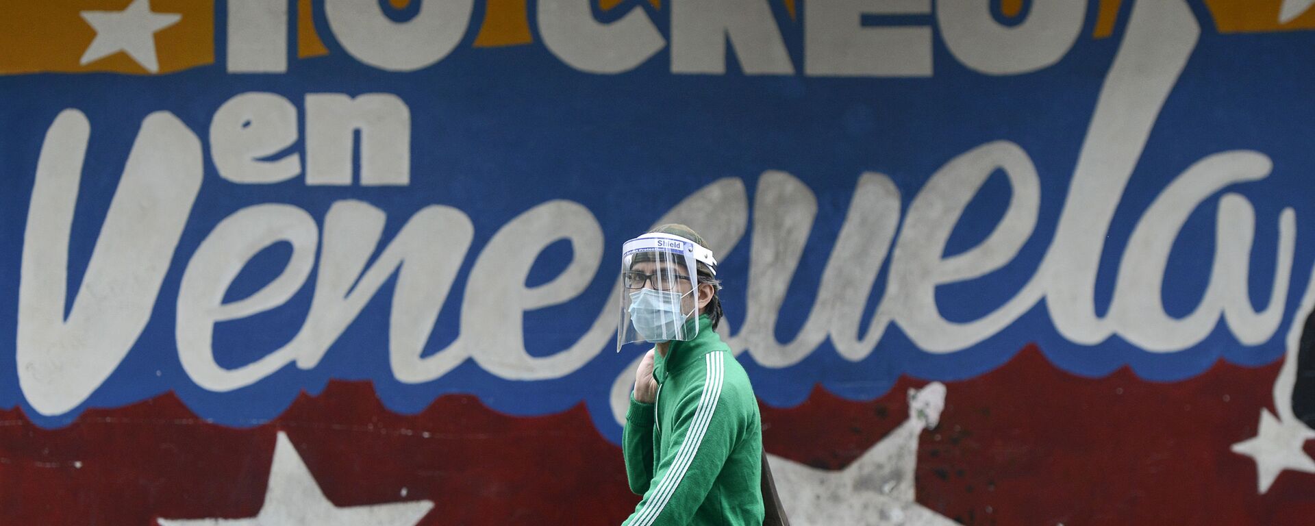 Un hombre pasa al lado de un mural en Caracas que dice yo creo en Venezuela - Sputnik Mundo, 1920, 27.05.2021