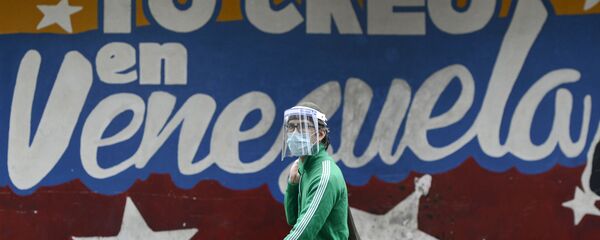 Un hombre pasa al lado de un mural en Caracas que dice yo creo en Venezuela - Sputnik Mundo