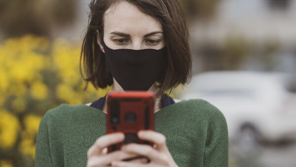 Mujer con mascarilla usando el celular - Sputnik Mundo