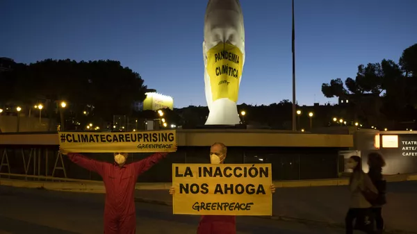 Activistas de Greenpeace colocan una mascarilla a una escultura gigante en la Plaza Colón 