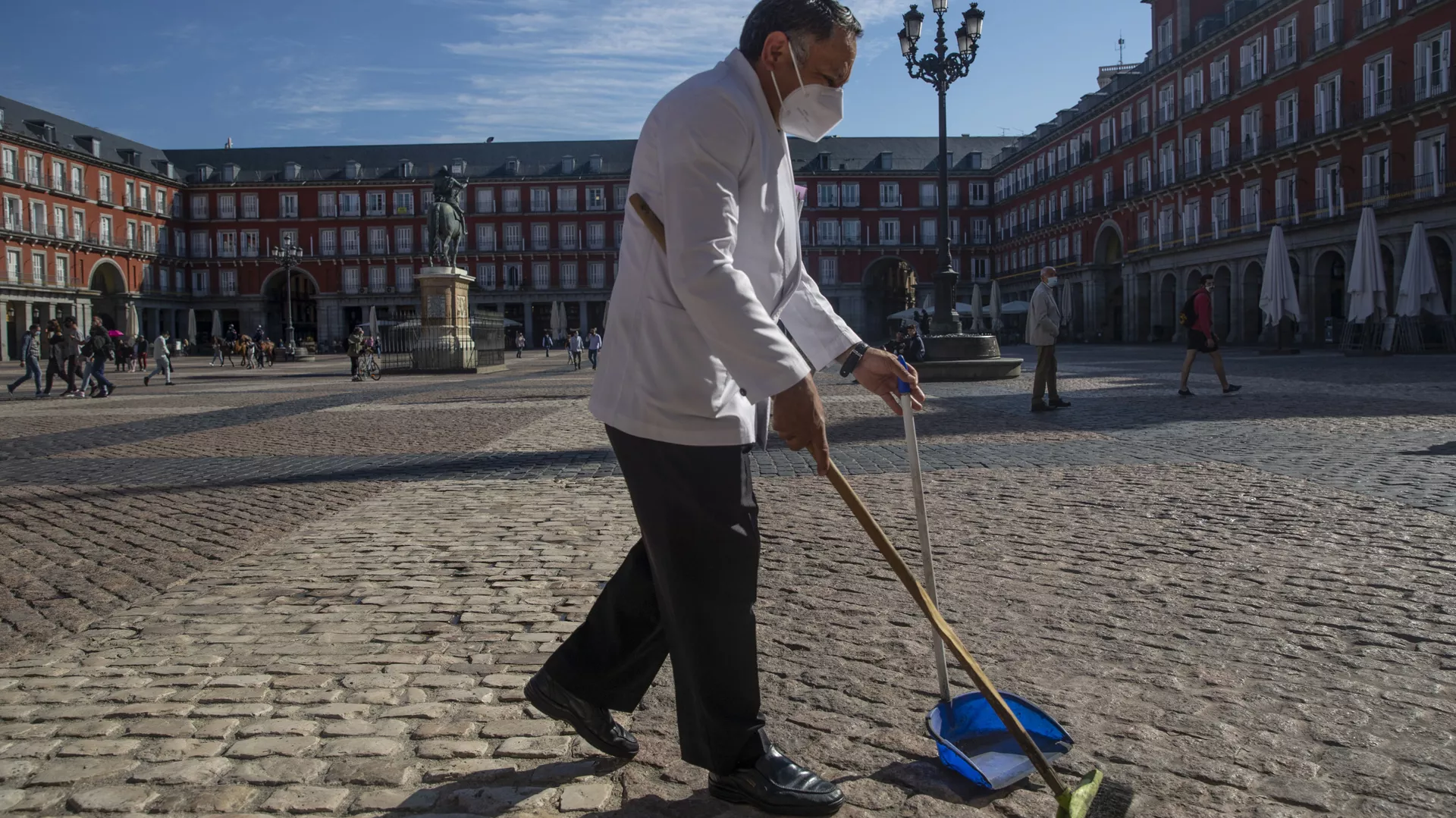 Un camarero con mascarilla limpiando en una de las terrazas de la Plaza Mayor de Madrid