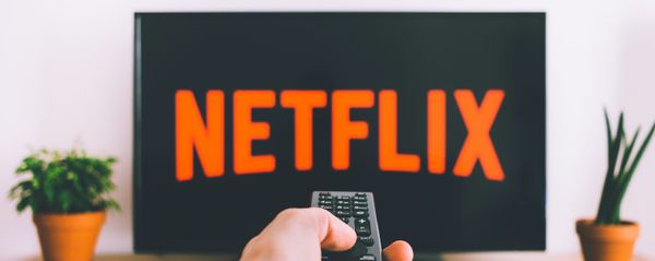 Una persona apunta con el control remoto a una pantalla de televisión con el logotipo de Netflix Una persona apunta con el control remoto a una pantalla de televisión con el logotipo de Netflix - Sputnik Mundo