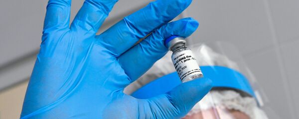 Una persona sostiene un frasco de la vacuna rusa Sputnik V - Sputnik Mundo