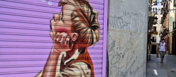 Una mujer pasa frente a una tienda cerrada en Madrid. 9 de julio de 2020 Una mujer pasa frente a una tienda cerrada en Madrid. 9 de julio de 2020 - Sputnik Mundo