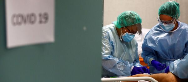 Trabajadores médicos atienden a un paciente infectado por COVID-19 en España - Sputnik Mundo