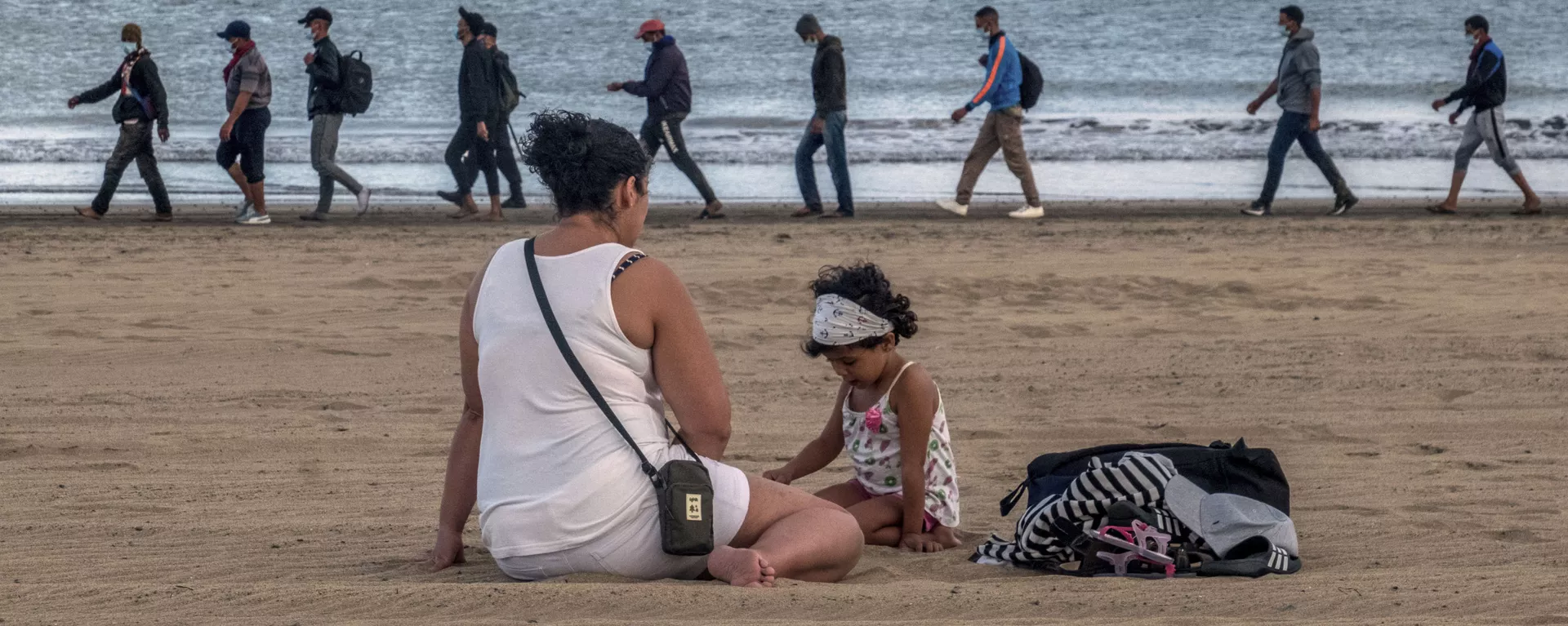 Migrantes caminan por la orilla escoltados por la Policía española tras llegar a la costa de Canarias (archivo) - Sputnik Mundo, 1920, 14.11.2022