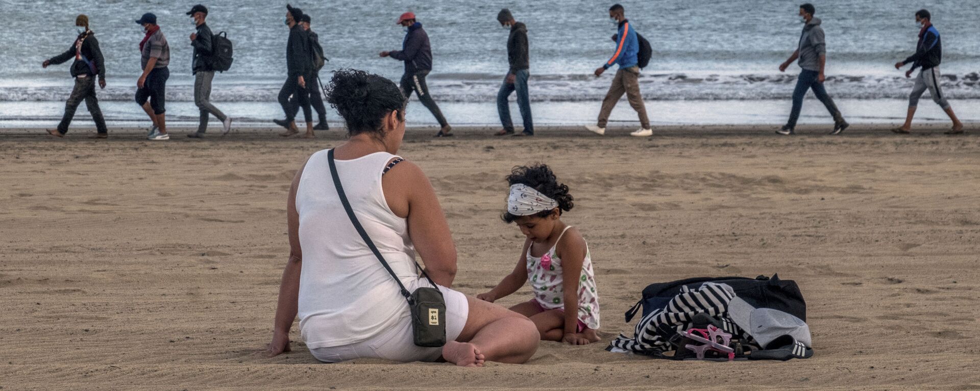 Migrantes caminan por la orilla escoltados por la Policía española tras llegar a la costa de Canarias (archivo) - Sputnik Mundo, 1920, 14.11.2022