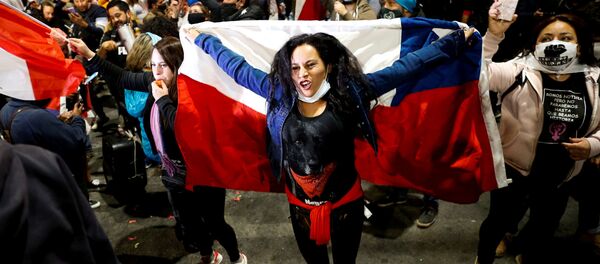 A woman holds a Chilean flag as she reacts to the referendum on a new Chilean constitution in Valparaiso - Sputnik Mundo