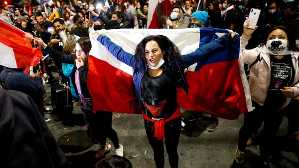 A woman holds a Chilean flag as she reacts to the referendum on a new Chilean constitution in Valparaiso