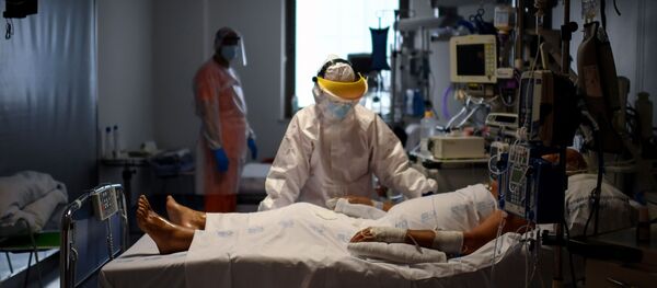 Sanitarios atendiendo a un paciente con coronavirus en España - Sputnik Mundo