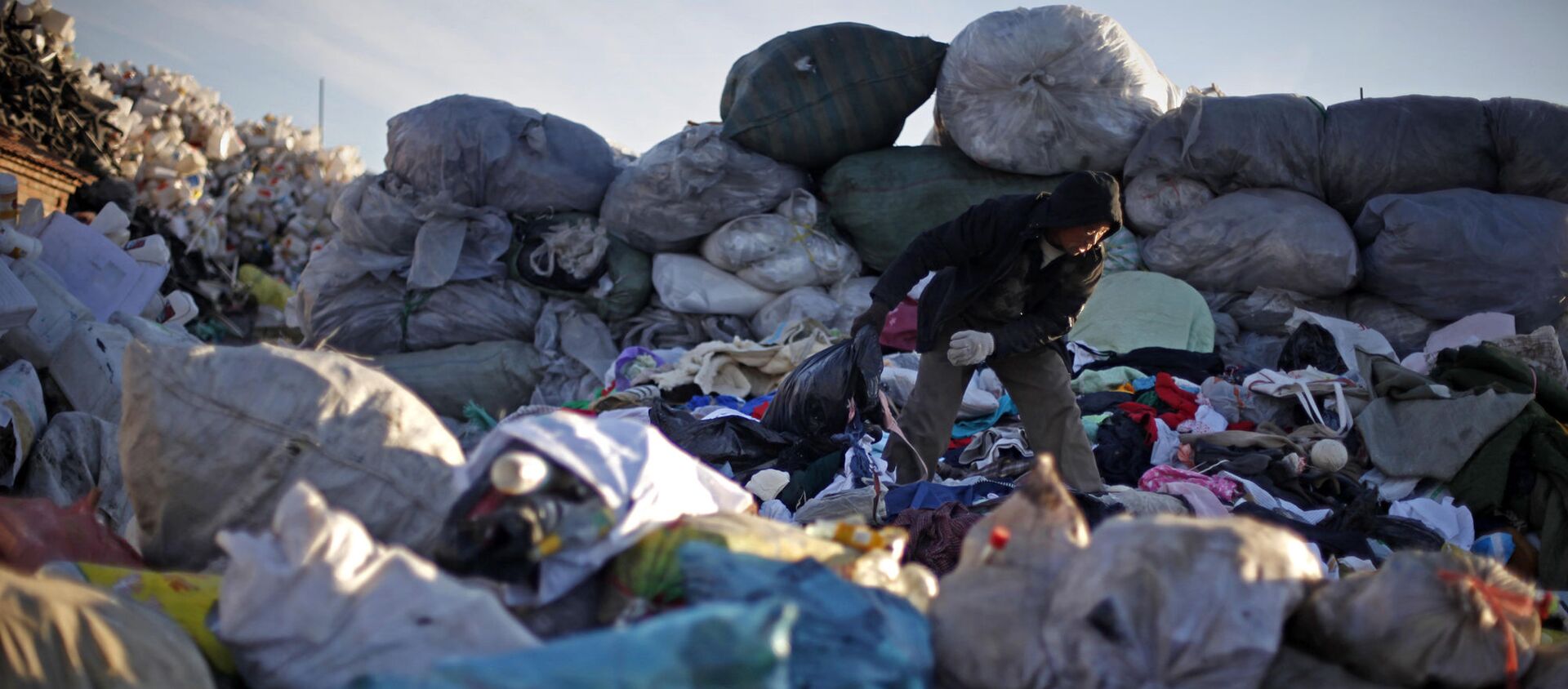 Un hombre chino revisa la ropa desechada en un centro de reciclaje en Pekín, China. - Sputnik Mundo, 1920, 28.10.2020