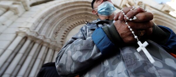 Un hombre reza frente a la iglesia de Notre Dame en Niza, Francia - Sputnik Mundo