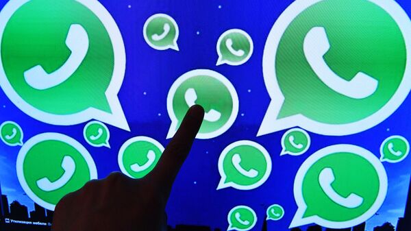 Una persona toca una pantalla en la que se ven diversos logotipos de la aplicación WhatsApp - Sputnik Mundo