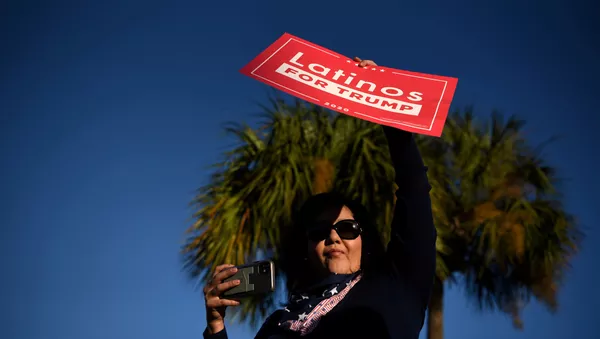 Una mujer sostiene un cartel que dice 'latinos por Trump'