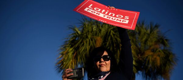 Una mujer sostiene un cartel que dice 'latinos por Trump' - Sputnik Mundo