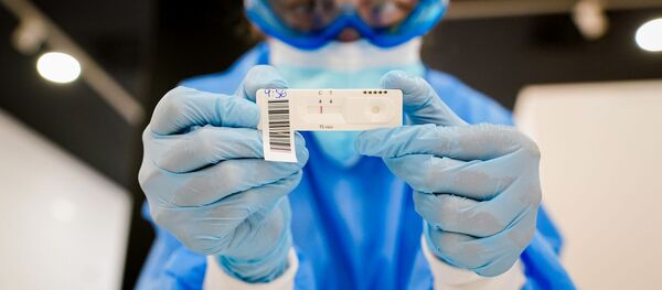 Una trabajadora de salud con una prueba de detección de COVID-19 en Madrid - Sputnik Mundo