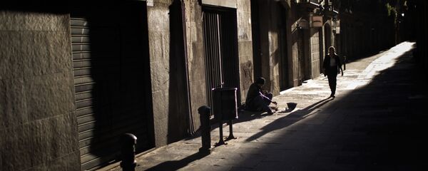 Una mujer pasa junto a un hombre que pide limosna en una calle del centro de Barcelona - Sputnik Mundo