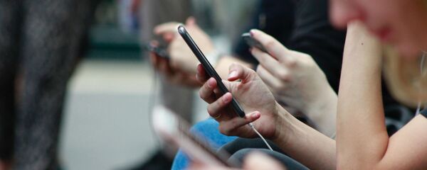 Unas personas utilizan sus teléfonos móviles - Sputnik Mundo