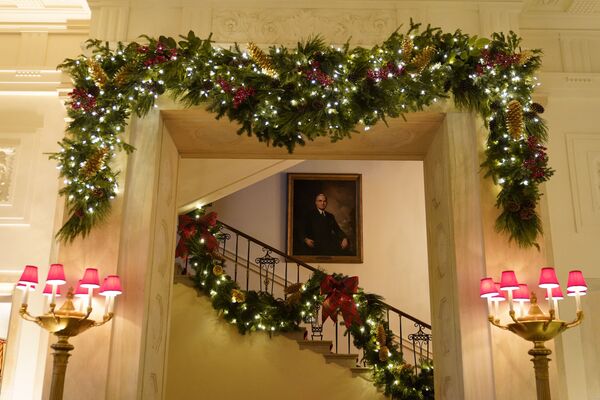 La primera dama también publicó fotos y vídeos de las decoraciones navideñas de la Casa Blanca en su cuenta de Twitter, escribiendo que fue decorada por voluntarios de toda América llenando sus habitaciones y salones con el espíritu de paz y alegría.En la foto: la Gran Escalinata de la Casa Blanca con la decoración navideña.  - Sputnik Mundo