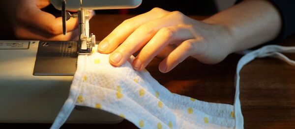 Una mujer cose una mascarilla de tela, referencial - Sputnik Mundo