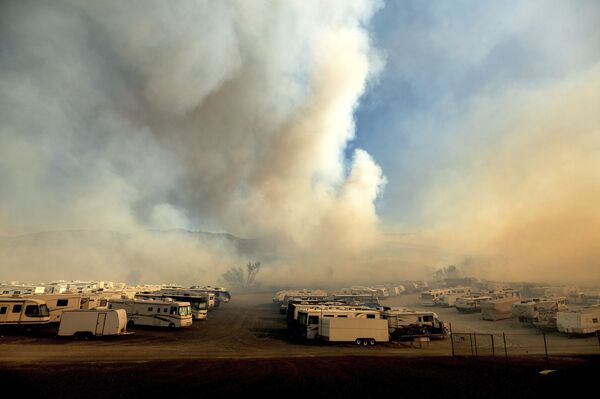 Como una prevención, las autoridades empezaron a cortar la electricidad para que no aparezcan nuevos focos debido a la ruptura de líneas eléctricas. En la foto: el humo provocado por los incendios forestales sobre el aparcamiento para autocaravanas en la orilla del lago de Irwin, en el condado de Orange, estado de California. - Sputnik Mundo