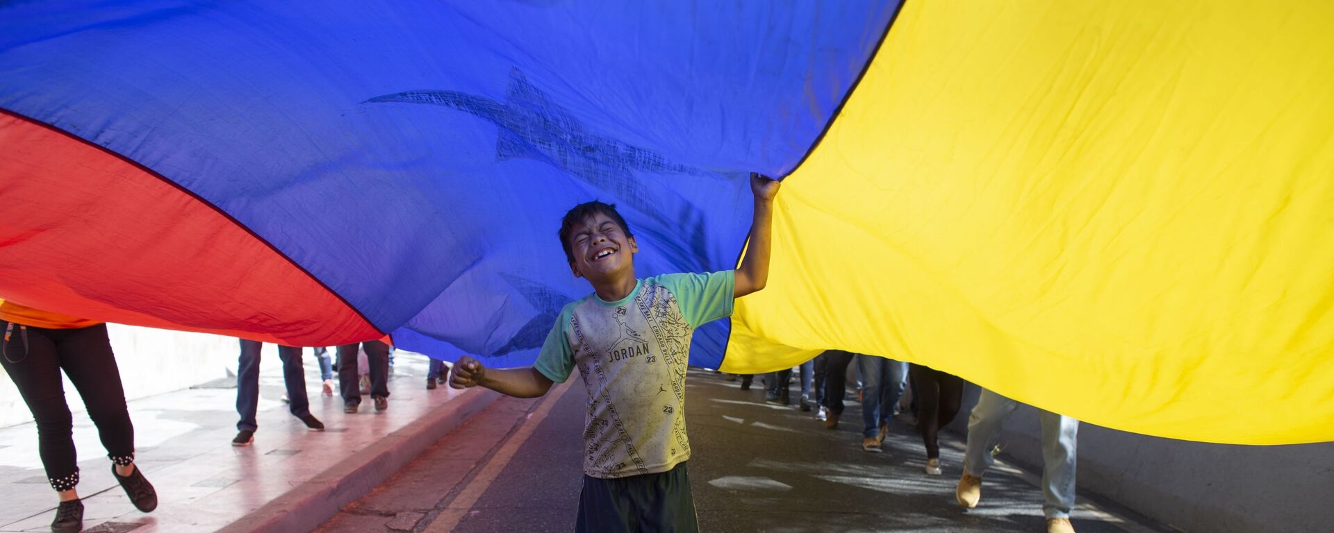 Un niño juega bajo una bandera venezolana - Sputnik Mundo, 1920, 28.11.2022