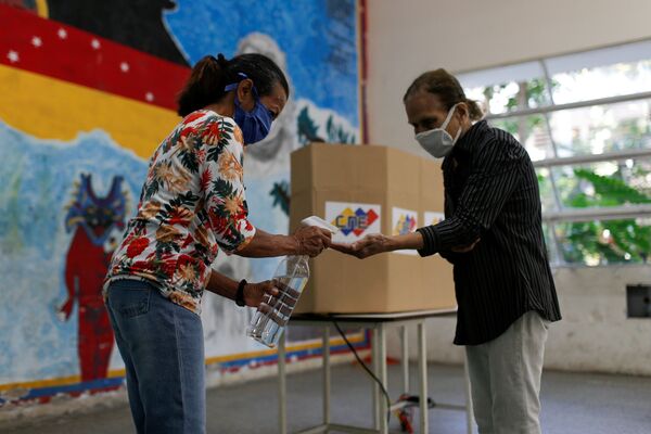 Los votantes desinfectan las manos en un centro de votación en Caracas - Sputnik Mundo