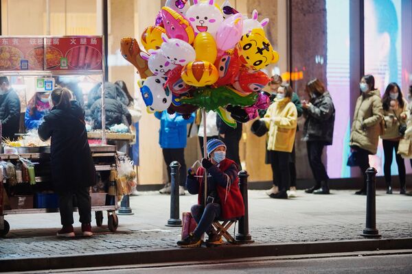 Los escolares tampoco usan mascarillas en clase, pero su temperatura se mide tres veces al día. Además, todas las aulas se desinfectan regularmente.En la foto: Una mujer vende globos inflables en una de las calles de Wuhan.   - Sputnik Mundo