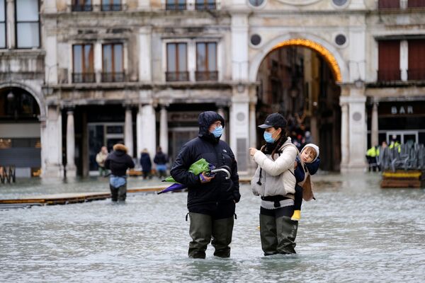 La anteiglesia de la catedral de San Marcos está completamente inundada. El guardián afirma que la situación es crítica. Hace un año, el agua entró incluso en las capillas interiores dañando los mosaicos y las columnas.En la foto: gente en la inundada plaza de San Marcos de Venecia.  - Sputnik Mundo