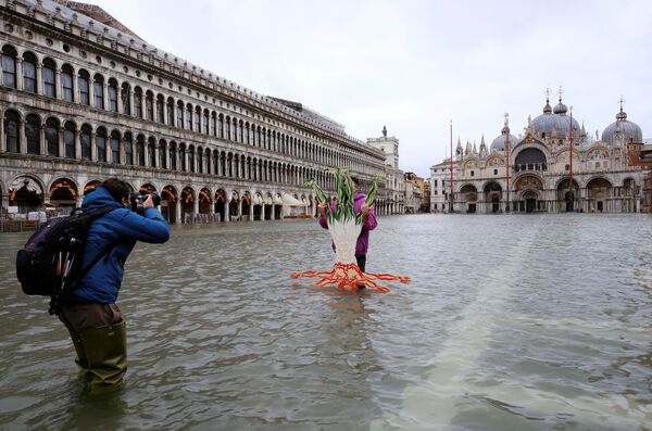 Afortunadamente, esta vez la situación no es tan catastrófica como hace un año. Se espera que el nivel del agua suba a 145 centímetros, mientras que el año pasado el nivel máximo fue de 187 centímetros.En la foto: la gente se toma fotos en la inundada plaza de San Marcos en Venecia. - Sputnik Mundo