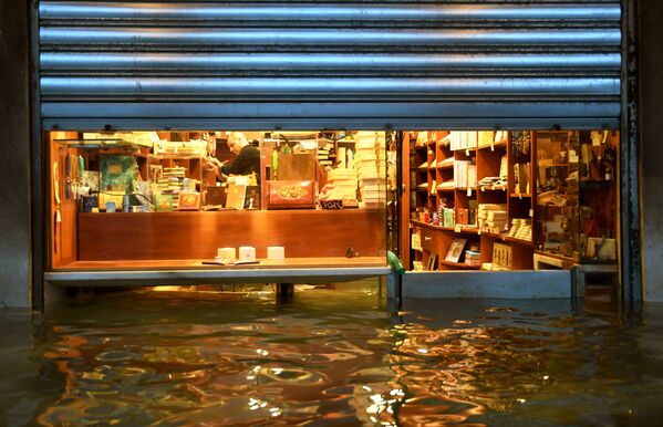 La anterior inundación dejó pérdidas a la ciudad por 1.000 millones de euros. Edificios históricos se inundaron y obras de arte únicas resultaron dañadas.En la foto: el dueño de una tienda cerca de la plaza de San Marcos en Venecia está tratando de protegerla de la inundación.  - Sputnik Mundo