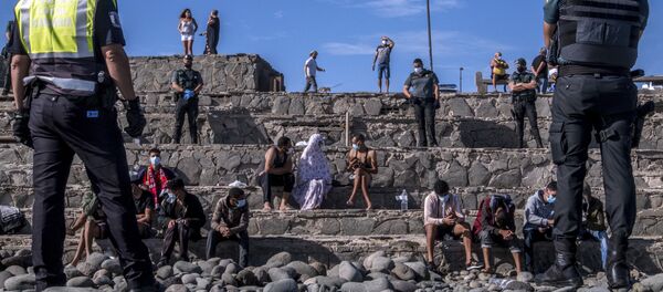 Migrantes son vigilados por la policía española después de llegar a la costa de las Islas Canarias, España. 23 de noviembre de 2020 - Sputnik Mundo