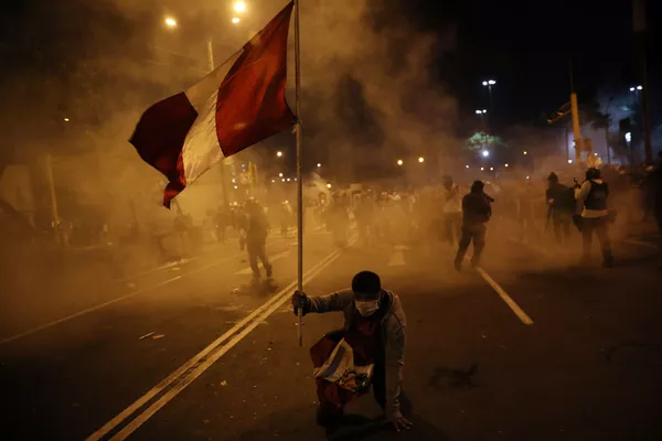 Un manifestante sostiene la bandera de Perú mientras la Policía reprime una protesta contra la destitución de Martín Vizcarra Un manifestante sostiene la bandera de Perú mientras la Policía reprime una protesta contra la destitución de Martín Vizcarra - Sputnik Mundo