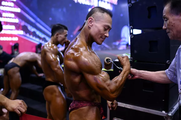 En 1994 se celebró en Shanghái el primer Campeonato Mundial de Culturismo entre los aficionados y ese mismo año se fundó la Asociación de Culturismo de Shanghái.En la foto: un competidor de la Federación Internacional de Halterofilia (IWF) Pekín 2020 se aplica una loción corporal especial antes de subir al escenario. En 1994 se celebró en Shanghái el primer Campeonato Mundial de Culturismo entre los aficionados y ese mismo año se fundó la Asociación de Culturismo de Shanghái.En la foto: un competidor de la Federación Internacional de Halterofilia (IWF) Pekín 2020 se aplica una loción corporal especial antes de subir al escenario. - Sputnik Mundo